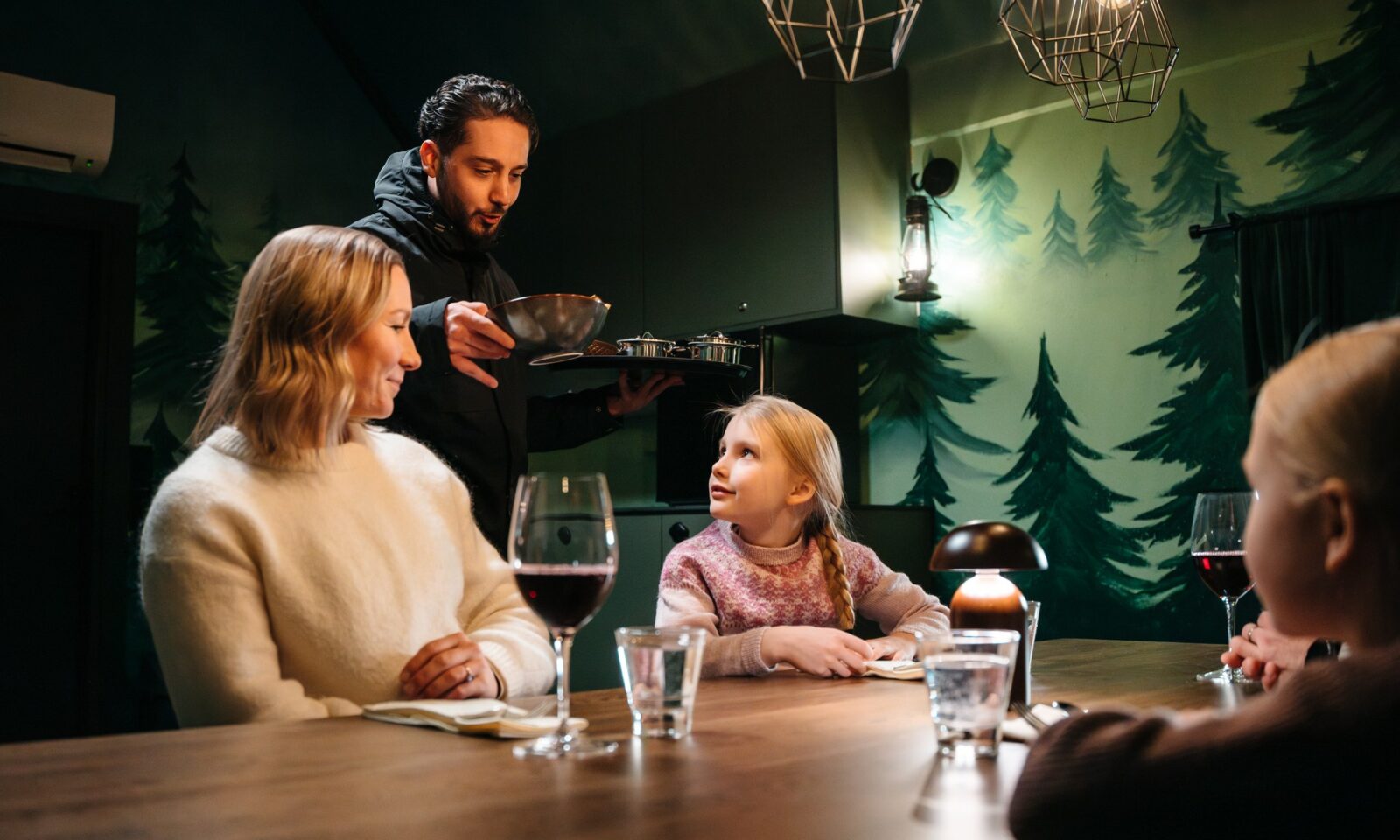 A waiter serving customers in the gingerbread cabin.