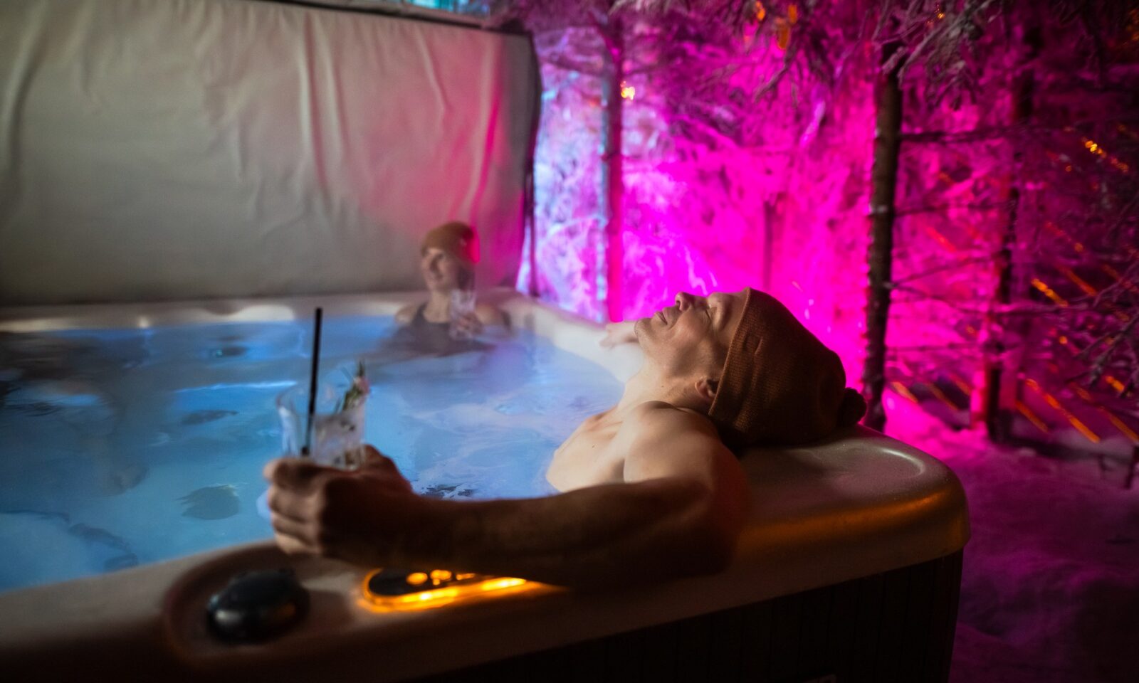 A man enjoying in jacuzzi with a drink in his hand.