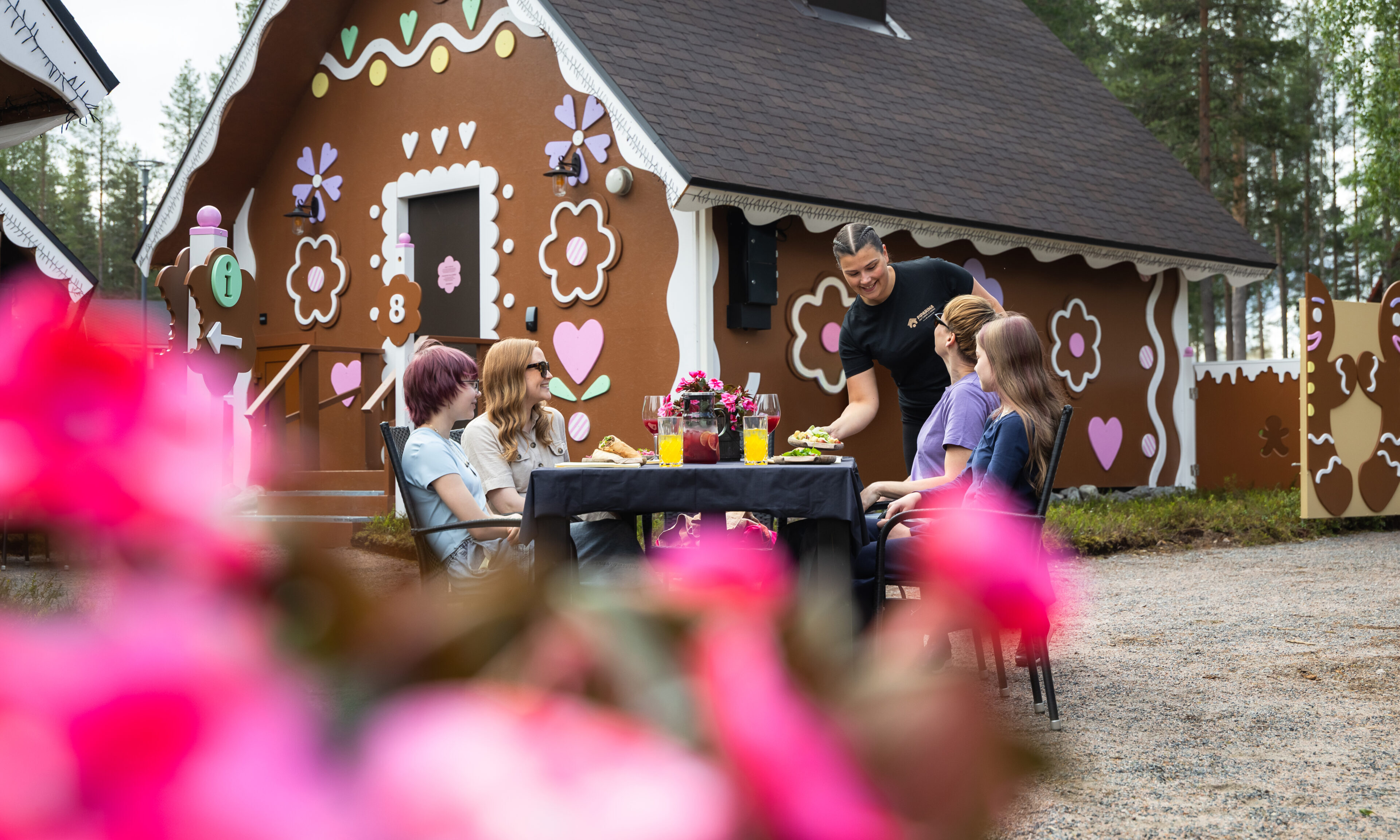 A member of the staff serving food to a group of friends at Piparina Summer Restaurant in Santa Claus Village, Rovaniemi.